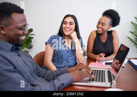 Tre diversi colleghi ridono e scherzano sul posto di lavoro, riunione amichevole Foto Stock