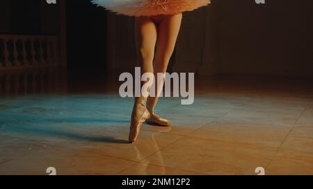 Primo piano cinematografico di aggraziati piedi da ballerino con scarpe a punta e tutu bianco. Danzatrice femminile in coreografia in opera. I treni della ballerina si muovono prima di uno spettacolo. Balletto classico art. Foto Stock