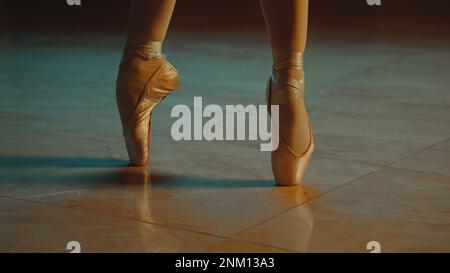 Primo piano cinematografico di aggraziati piedi da ballerino con scarpe a punta e tutu bianco. Danzatrice femminile in coreografia in opera. I treni della ballerina si muovono prima di uno spettacolo. Balletto classico art. Foto Stock