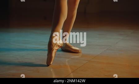 Primo piano cinematografico di aggraziati piedi da ballerino con scarpe a punta e tutu bianco. Danzatrice femminile in coreografia in opera. I treni della ballerina si muovono prima di uno spettacolo. Balletto classico art. Foto Stock