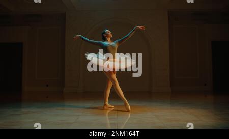 Ripresa cinematografica di una bella ballerina classica femminile in tutu bianco che balla nella lobby del teatro e si prepara ad iniziare lo spettacolo. Coreografia prima dell'inizio dello spettacolo. Balletto classico art. Foto Stock