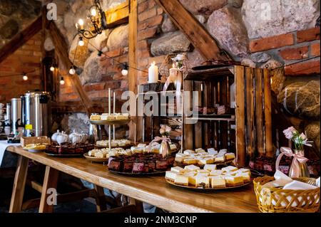 interni e decorazioni per matrimoni a buffet con dolci e dolci in stile bohémien e rustico Foto Stock