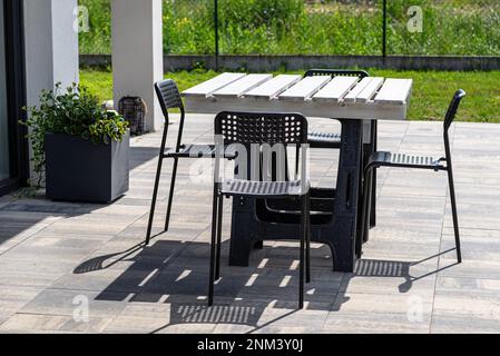 Tavolo da terrazza in pallet bianco su tralicci di plastica, sedie di plastica nera. Foto Stock