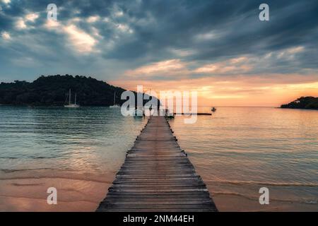 Bellissimo tramonto sul molo di legno e barca nel mare tropicale a Koh Kood Island Foto Stock