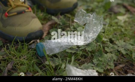 Giovane uomo che pulisce su bottiglie di plastica gettate sul terreno- primo piano, concetto di pulizia ambientale Foto Stock