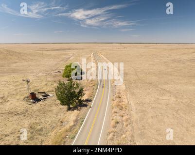 Ampie praterie aperte con una strada al centro con alberi isolati in fattoria durante il giorno con cielo nuvoloso, terreni agricoli rurali e praterie negli Stati Uniti Foto Stock