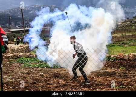 Nablus, Palestina. 24th Feb, 2023. Un dimostratore palestinese lancia un barattolo di gas lacrimogeno dopo che i soldati israeliani lo hanno sparato contro di lui durante la manifestazione contro gli insediamenti israeliani nel villaggio di Beit Dajan vicino alla città di Nablus in Cisgiordania. Credit: SOPA Images Limited/Alamy Live News Foto Stock