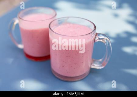 Due frullati di frutta rosa in bicchieri di vetro si trovano su un tavolo in un bar sulla strada Foto Stock