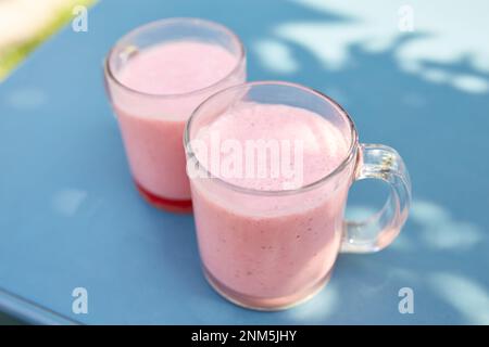 Due frullati di frutta rosa in bicchieri di vetro si trovano su un tavolo in un bar sulla strada Foto Stock