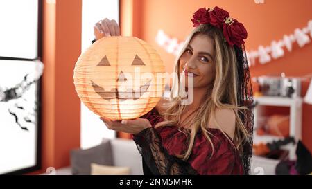 Giovane donna bionda che indossa il costume di katrina tenendo la lampada di zucca in casa Foto Stock