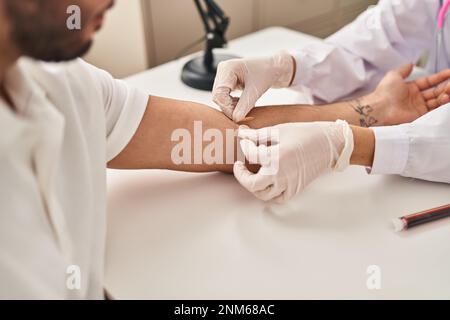 L'uomo e la donna che indossano l'uniforme del medico che hanno analisi del sangue in clinica Foto Stock