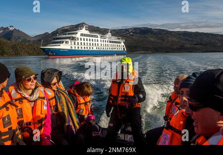 Ventus nave da crociera passeggeri viaggiano Zodiac di sbarcare e di esplorare Ainsworth Bay, in background Ventus nave da crociera,Tierra del Fuego, Patagonia, Cile Foto Stock