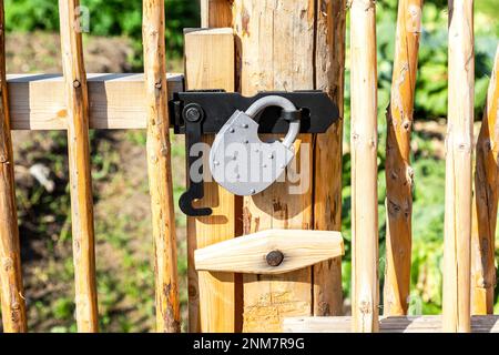 Nuovo lucchetto di metallo su una recinzione di legno giallo brillante nel villaggio Foto Stock