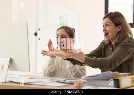 Le donne in ufficio gioiscono guardando lo schermo del computer Foto Stock