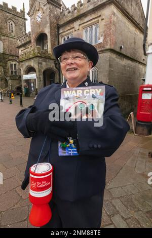 Inghilterra, Dorset, Shaftesbury, Salvation Army Lady Selling Copies of the War Cry Magazine Foto Stock