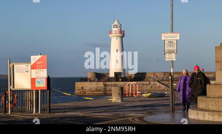 Donaghadee, County Down, Irlanda del Nord, Regno Unito. 24 Feb 2023. Tempo nel Regno Unito - un pomeriggio di sole luminoso ma un forte vento sulla costa orientale dell'Irlanda del Nord. Un gruppo di donne si è ben avvolto contro il tempo camminando sul molo del porto. Credit: CAZIMB/Alamy Live News. Foto Stock