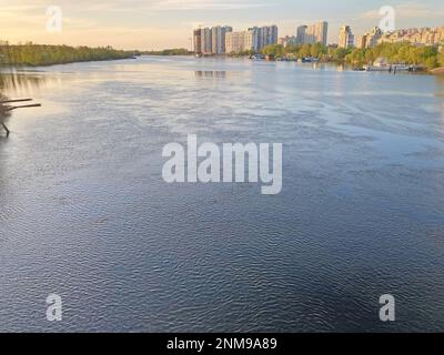 Splendida vista panoramica della città del fiume Kyiv Dneper al tramonto su acqua blu scuro con i raggi luminosi riflessi del sole, copia-spazio. Vista di Foto Stock