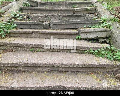 una vecchia scalinata in pietra fatiscente che porta in cima a un prato. una vecchia scalinata in pietra fatiscente con scalini alla cima coltivata con erba da Foto Stock