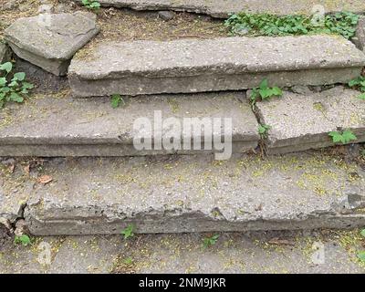 una vecchia scalinata in pietra fatiscente che porta in cima a un prato. una vecchia scalinata in pietra fatiscente con scalini alla cima coltivata con erba da Foto Stock