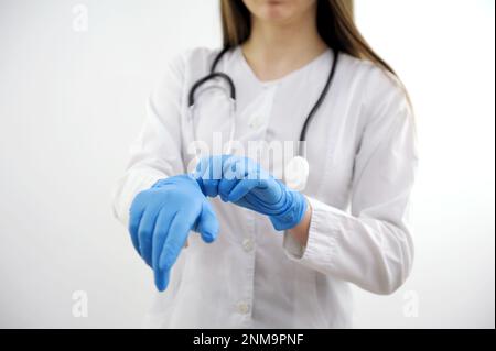 L'uomo bianco che è medico indossa guanti medici blu sulle sue mani. Foto studio su sfondo grigio. Orizzontale. Foto di alta qualità Foto Stock