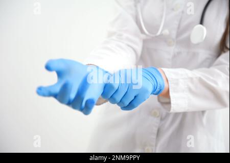 Primo piano mani scienziate mettere in nitrile guanti in lattice blu in camice indossare guanti in nitrile, facendo esperimenti in laboratorio. Foto di alta qualità Foto Stock