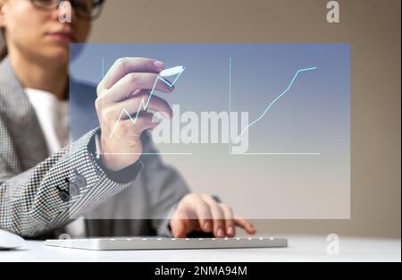 Persona di lavoro femminile che lavora con grafici finanziari utilizzando la penna digitalizzata stilo e lo schermo virtuale. Grafico di crescita finanziaria Foto Stock