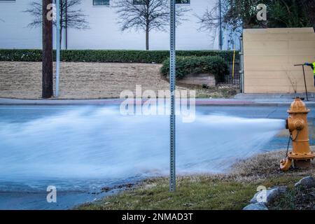 L'idrante del fuoco sgorga l'acqua mentre rilascia la pressione e fa uscire  i tubi dell'acqua. L'erba circonda l'idrante. Il tappo si trova  sull'idrante Foto stock - Alamy