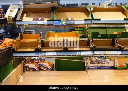 Scaffali vuoti scatole casse con pochi sacchetti di plastica rimasti di patate britanniche gallesi sullo scaffale del supermercato Lidl 24 febbraio 2023 Galles UK KATHY DEWITT Foto Stock