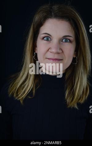 ritratto di una bella donna bionda con gli occhi spalancati e un lieve sorriso Foto Stock