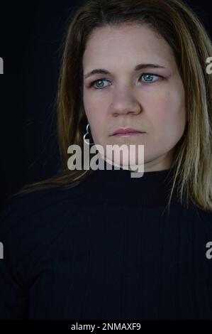 ritratto di una bella donna bionda con uno sguardo molto triste che guarda via nello spazio Foto Stock