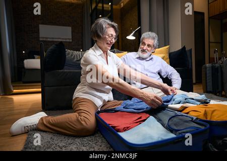 Moglie che aiuta il marito a piegare i vestiti in borsa Foto Stock