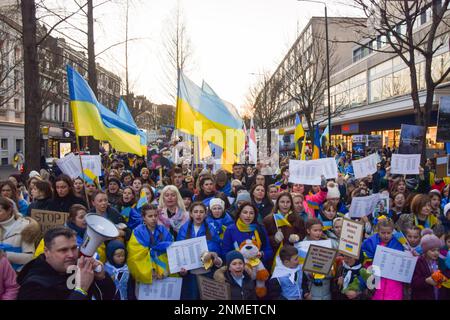 Londra, Regno Unito. 24th febbraio 2023. I manifestanti che hanno i segni con i nomi dei bambini uccisi negli attacchi russi passano attraverso Notting Hill Gate. Migliaia di persone hanno marciato dall'Holland Park all'ambasciata russa durante una protesta pro-Ucraina per il primo anniversario dell'invasione russa. Foto Stock