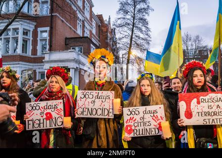 Donna con corone floreali in possesso di 365 giorni di guerra sofferenza cartelloni al 'heartbroken ma unbroken', ricordo evento che segna l'anniversario di R Foto Stock