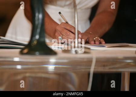 La sposa firma i documenti di registrazione del matrimonio Foto Stock