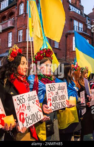 Donna con corone floreali in possesso di 365 giorni di guerra sofferenza cartelloni al 'heartbroken ma unbroken', ricordo evento che segna l'anniversario di R Foto Stock