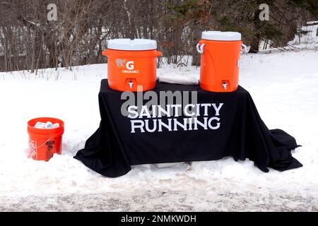 I corridori si fermano con i contenitori Gatorade su un tavolo nella neve situato sul sentiero North Mississippi River Boulevard. St Paul Minnesota, Minnesota, USA Foto Stock
