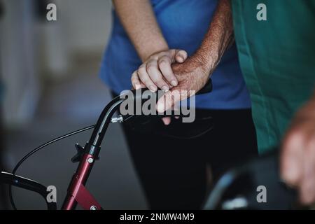 Grazia theres nella cura. un'infermiera che assiste la sua paziente anziana che usa un camminatore per il supporto. Foto Stock