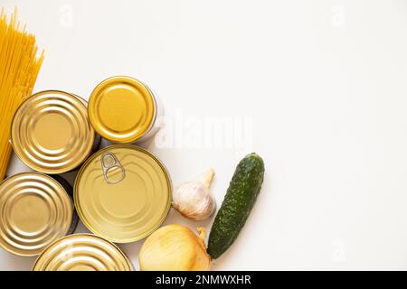 Cibi in scatola diversi, spaghetti e cipolle, cetriolo e aglio su fondo bianco, un set di prodotti si trova su un bianco Foto Stock