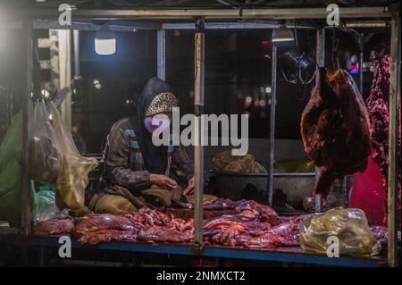 Una donna musulmana prepara la carne cruda da vendere al principale mercato all'ingrosso di verdure e carne, Phsar Dumkor, di notte a Phnom Penh, Cambogia. © Kraig Lieb Foto Stock