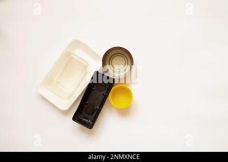 Vari vasi in plastica e in scatola e vecchie confezioni giacciono su uno sfondo bianco, contenitori per alimenti Foto Stock