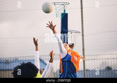 Netball, tiro al bersaglio e difesa di un gruppo di atlete su un campo sportivo all'aperto. Mira, gioco sportivo e sfida partita di una persona nera con un Foto Stock