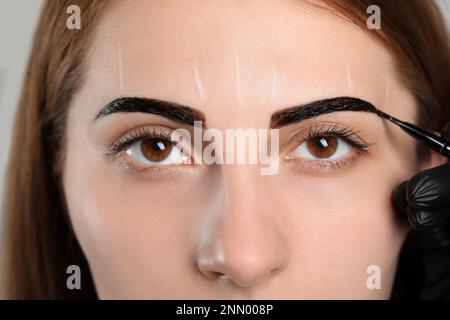 Estetista applicare la tinta durante la procedura di correzione sopracciglia, primo piano Foto Stock