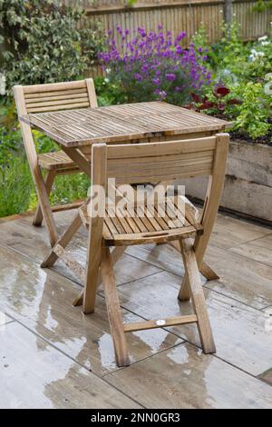 Tavolo pieghevole in legno e sedie sul patio in giardino sotto la pioggia. Regno Unito maggio Foto Stock