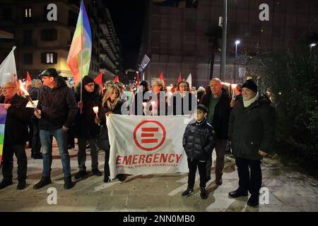 Persone con bandiere di pace , segni di protesta e torce partecipano a un incontro e marcia per chiedere la fine della guerra in Ucraina. Foto Stock