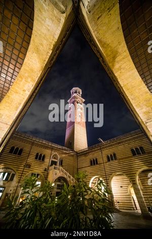 La Torre dei Lamberti, una torre di Verona alta 84 m, vista dal cortile cortile del mercato Vecchio, illuminata di notte. Foto Stock