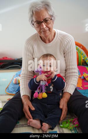 Ritratto bambino seduto sul pavimento a giocare con la nonna a casa Foto Stock