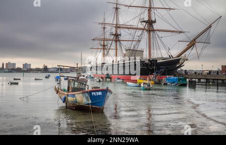 Una piccola barca da pesca chiamata Mizpah III ormeggiata nel porto di Portsmouth di fronte alla famosa nave da guerra HMS Warrior, la prima nave navale in ferro nella w Foto Stock