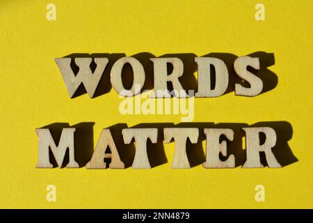 Le parole contano, frase in lettere di alfabeto di legno isolate su sfondo giallo Foto Stock