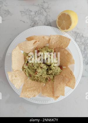 Vista dall'alto di nachos e guacamole messicano con limone Foto Stock