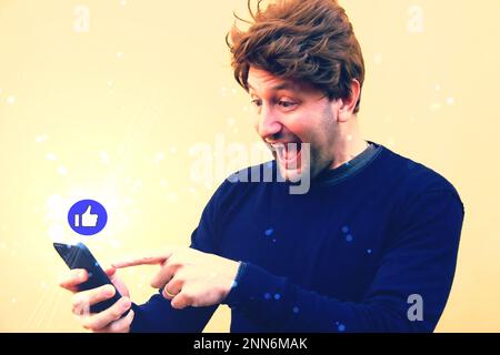 Uomo d'affari che utilizza l'icona mobile online connessione di social networking sullo schermo , felice metà età barbuto uomo che utilizza uno smartphone con l'icona 'mi piace' e. Foto Stock